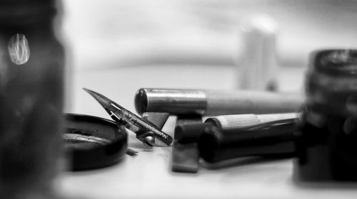 Primer plano en blanco y negro de una pluma de caligrafía y herramientas de escritura en el taller de la Asociación Asturias Caligrafía.