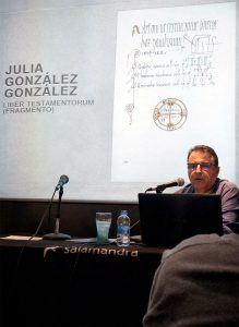 Conferencia de Andrés Antón en exposicion FNAC – Asturias Caligrafía Andrés Antón impartiendo una charla con micrófono y ordenador portátil, con una proyección de fondo sobre el "Liber Testamentorum" y la obra de Julia González, en un evento de Asturias Caligrafía en FNAC.